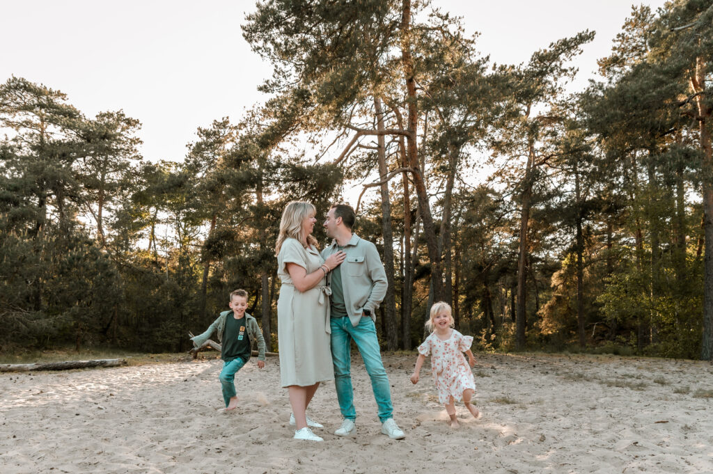 Spontane gezinsfoto van een gezin met jonge kinderen. De foto is genomen in de bossen en duinen van de Loonse en Drunense duinen, door Moment Fotografie