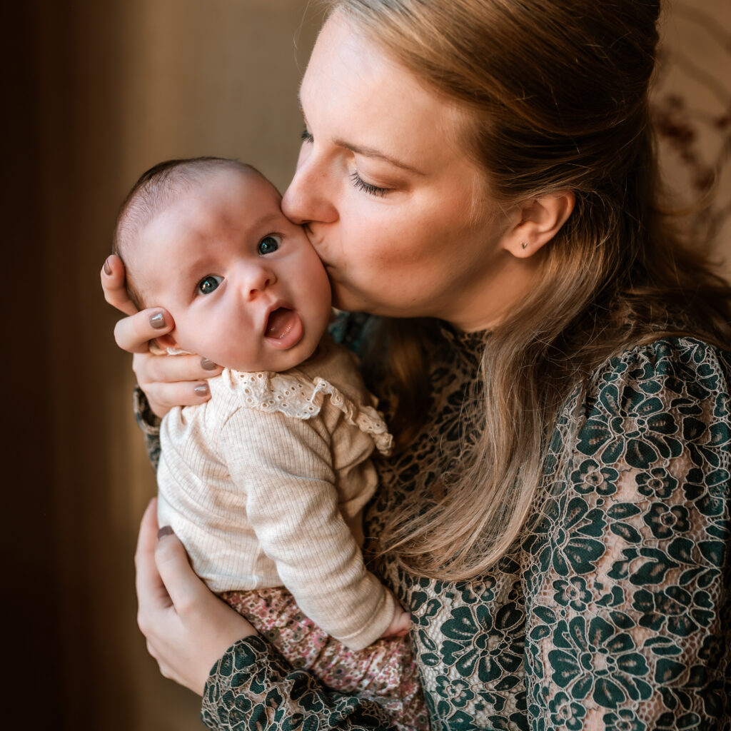 Newborn die op de wang gekust wordt door haar moeder.