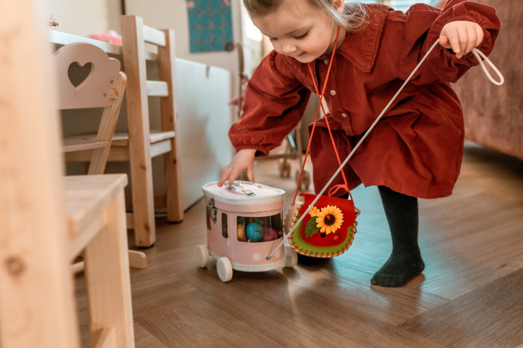 Meisje in rode jurk speelt met een trekfiguurtje